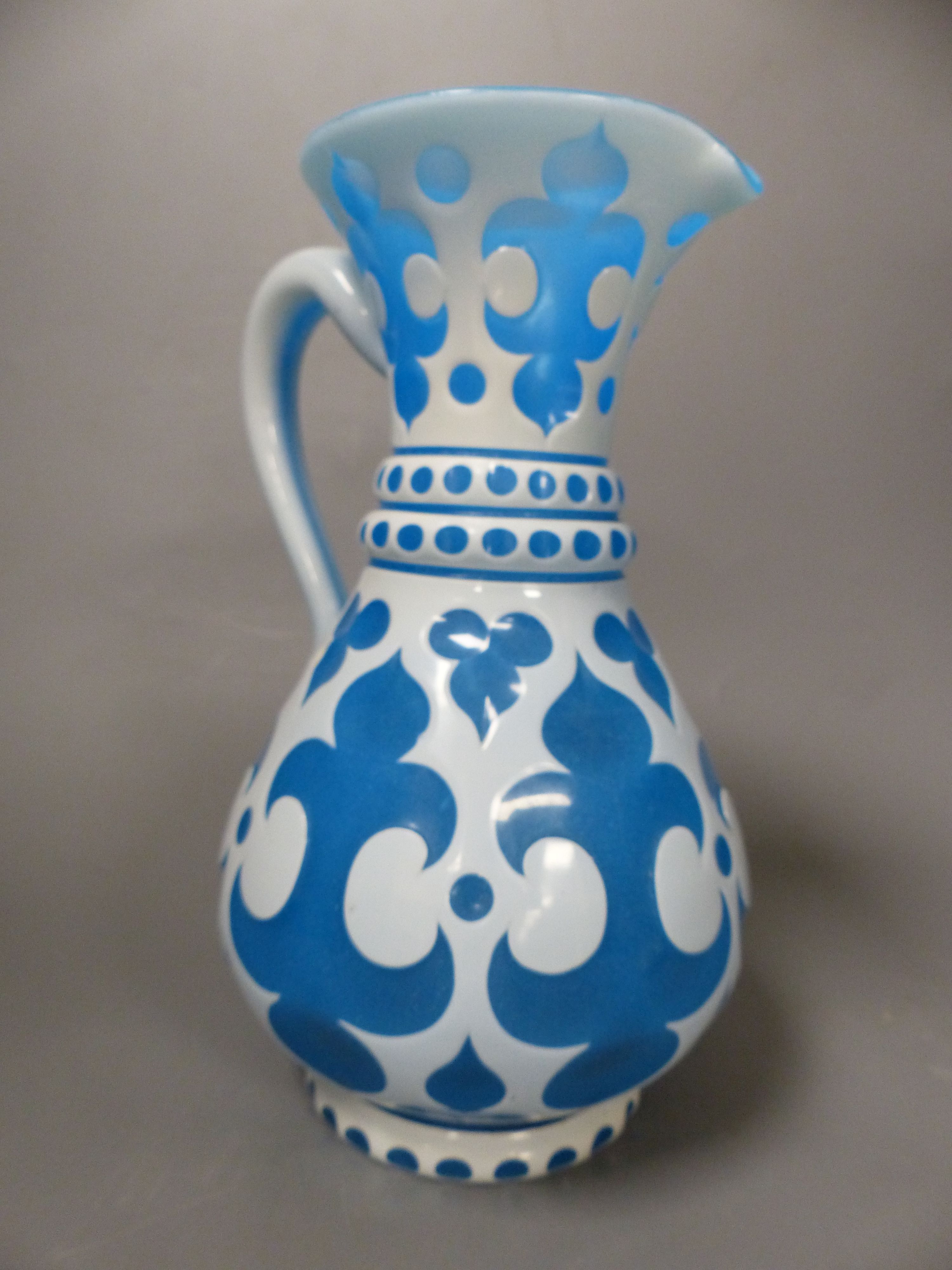 A Bohemian blue and white overlaid glass jug and a similar ruby and white overlaid glass vase, tallest 35cm